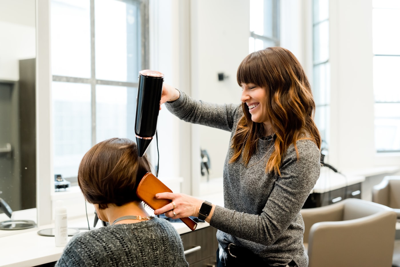 A stylist blow-drying a guest's hair at the styling counter.